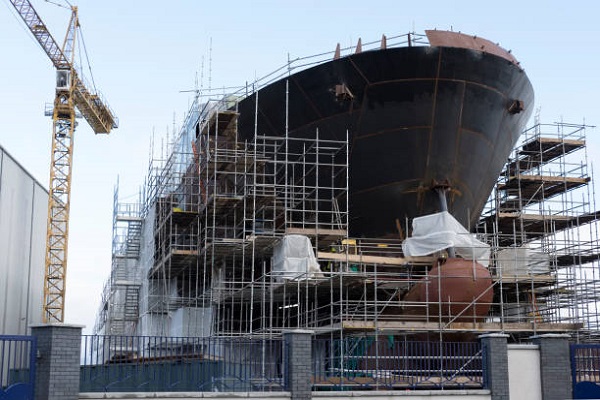 Shipbuilding progress scaffolding and crane large nautical vessel being built at dock port harbour harbour Glasgow traditional industry